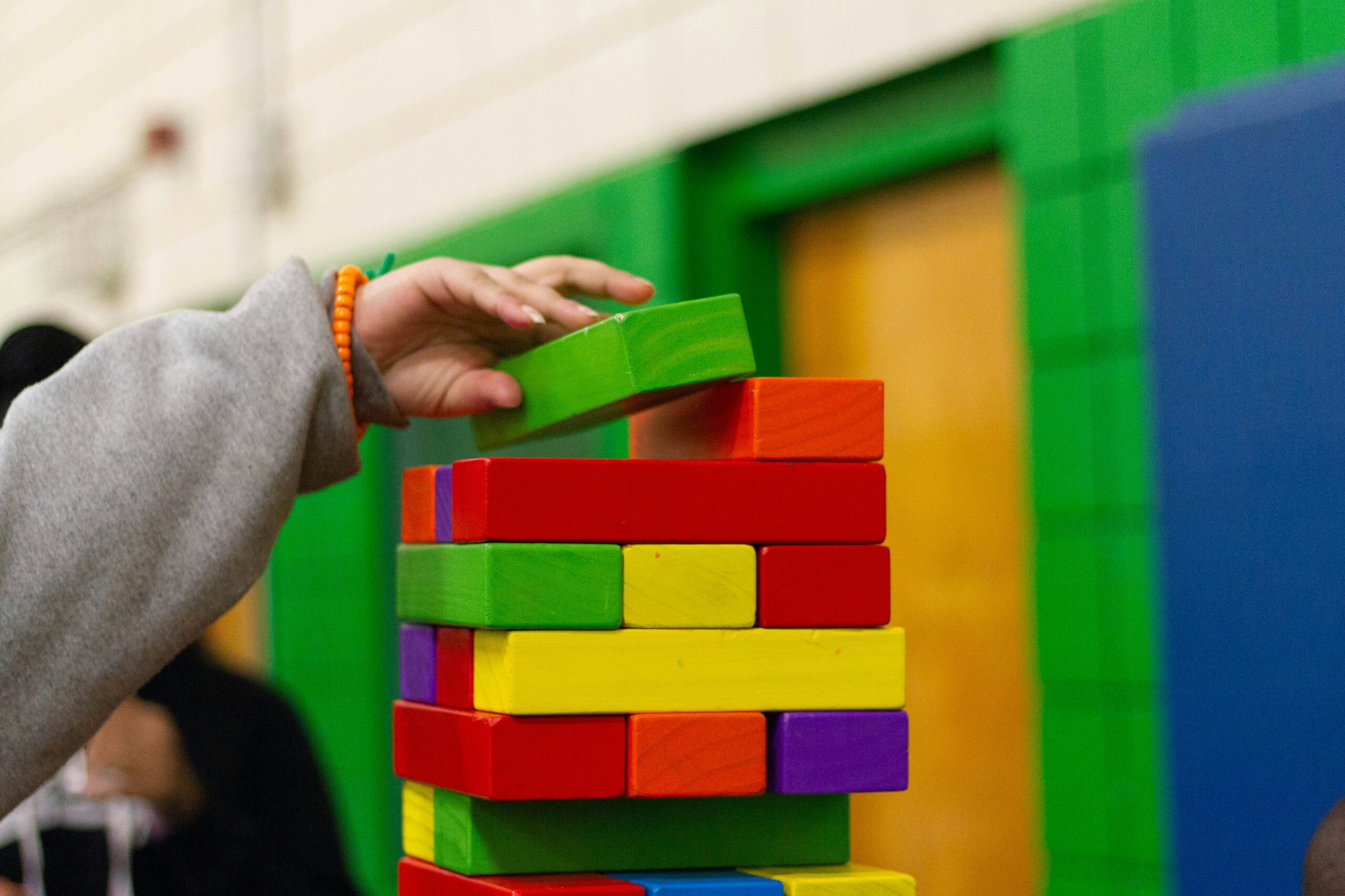 Brinquedos educativos com formas e cores: torre de argolas, labirinto de contas e xilofone.